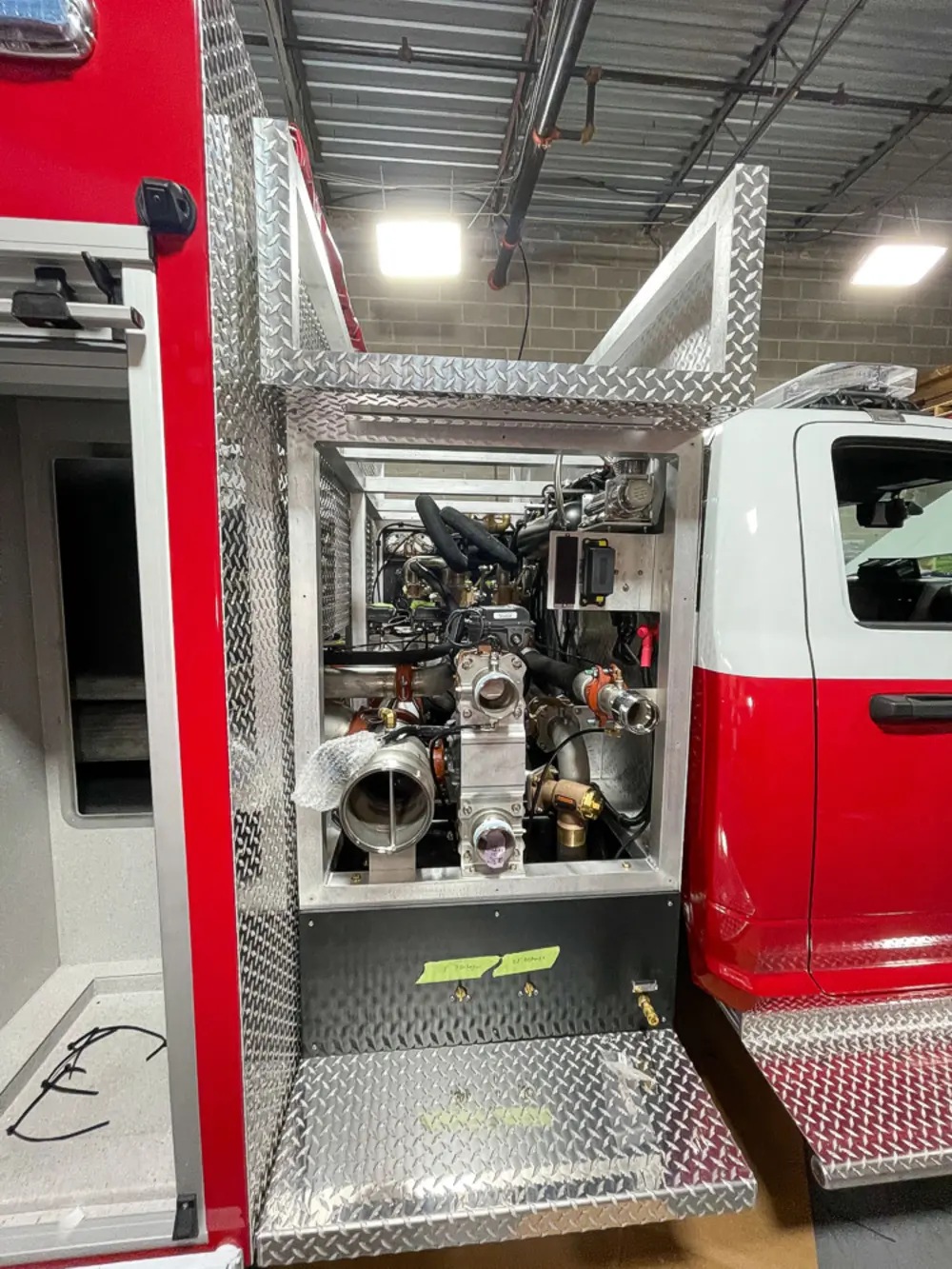 Exterior view of small fire truck showing cab, body compartments, and wheel/tire area.